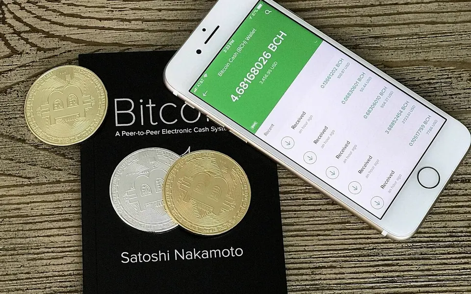A physical bitcoin token beside a phone showing a wallet