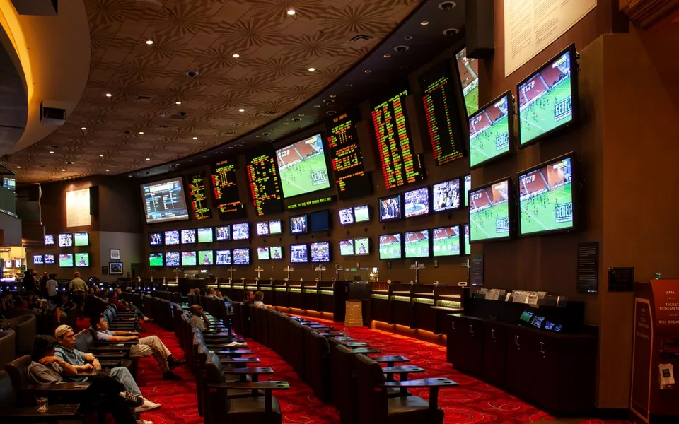 A wall of odds screens above the counter of a sportsbook